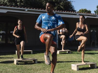 Outdoor fitness class with instructor and participants on platforms.