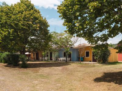 Colorful houses among trees, with white chairs outside.