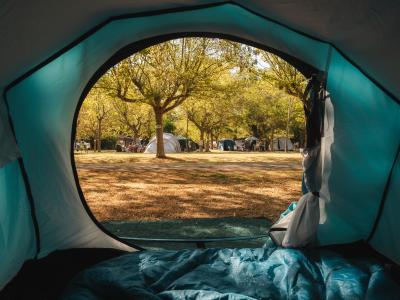 Vista dall'interno di una tenda su un campeggio soleggiato.