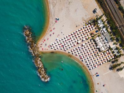 Spiaggia affollata con ombrelloni e mare turchese, vista dall'alto.