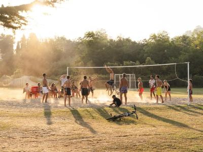 Giovani giocano a pallavolo sulla sabbia al tramonto.