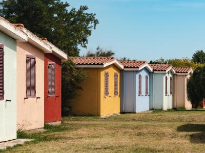 Casette colorate allineate su un prato verde sotto un cielo azzurro.