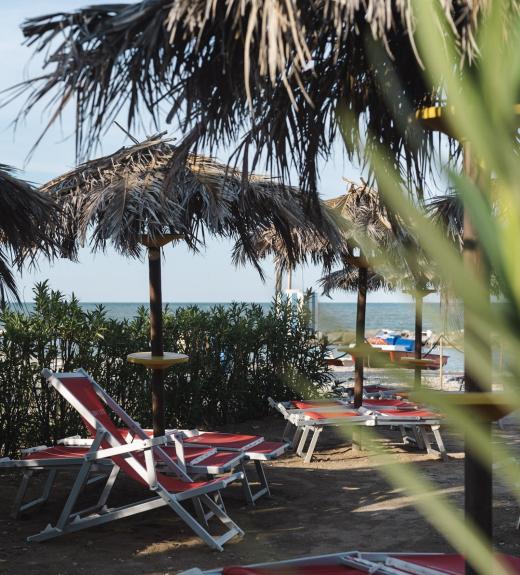 Beach with straw umbrellas and red loungers near the sea.