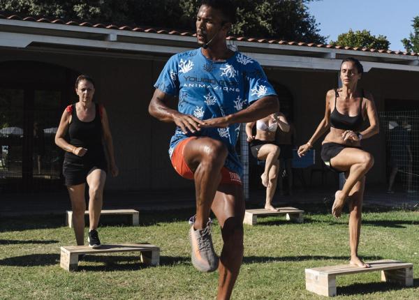 Outdoor fitness class with instructor and participants on platforms.