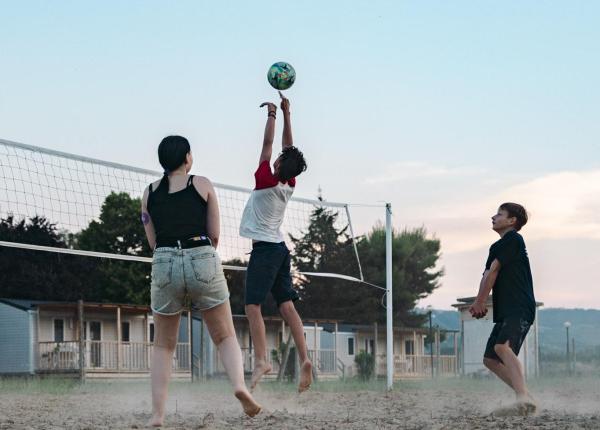 Three people playing volleyball on an outdoor court.