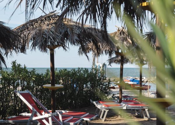 Beach with straw umbrellas and red loungers near the sea.