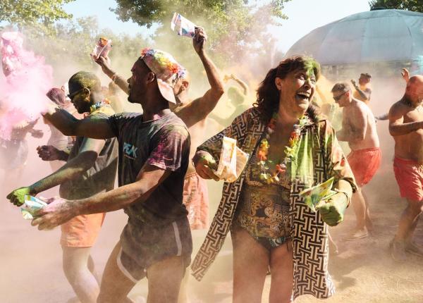 Persone festeggiano lanciando polveri colorate all'aperto.