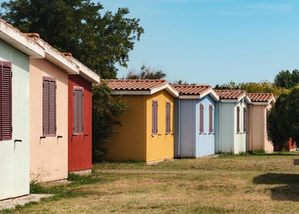 Casette colorate allineate su un prato verde sotto un cielo azzurro.