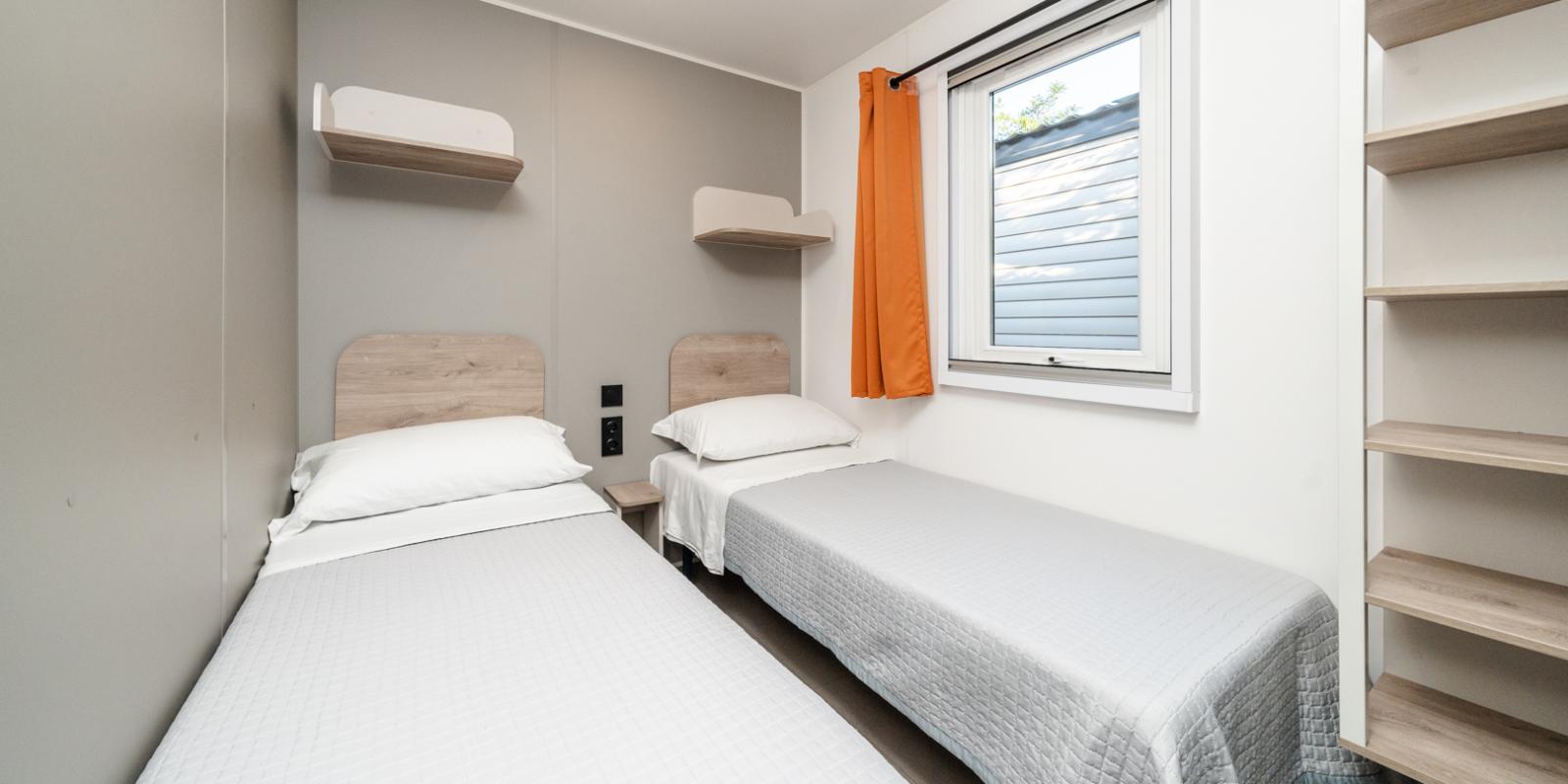 Simple room with two single beds, shelves, and a window.