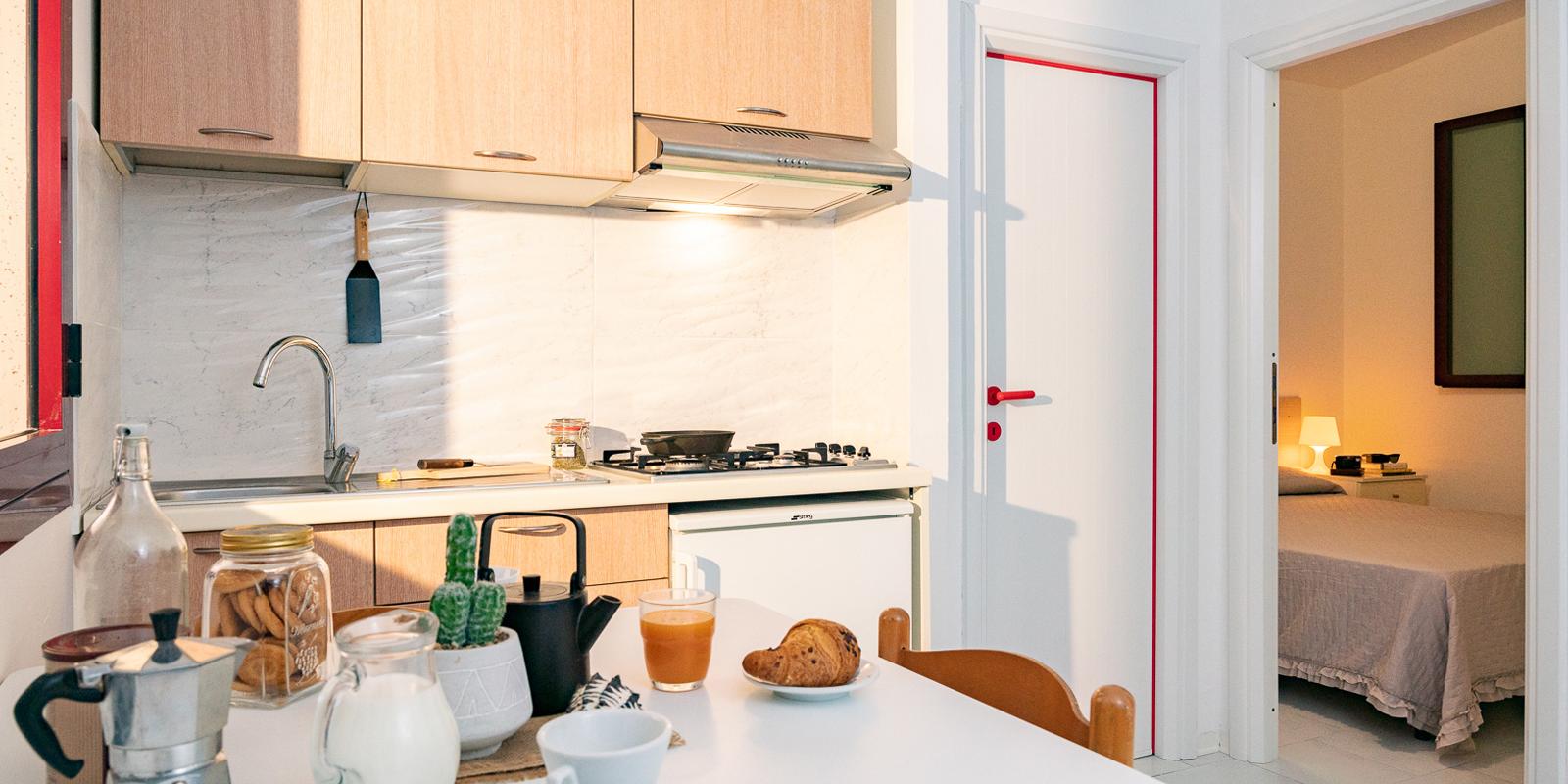 Cucina moderna con colazione pronta, vista sulla camera da letto.