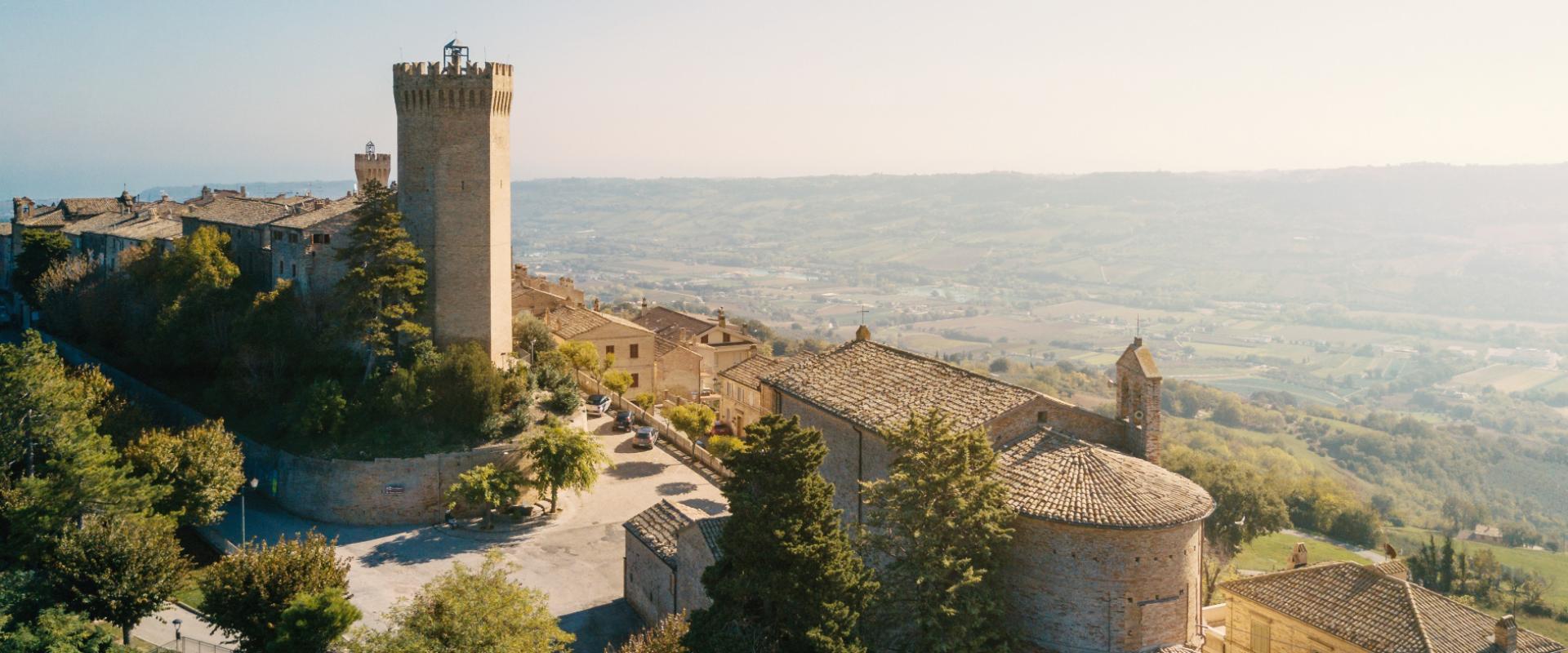 Vista panoramica di un borgo medievale con una torre e case in pietra.