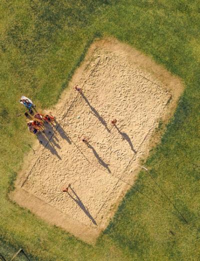 Vista aerea di un campo da pallavolo con persone che giocano sulla sabbia.