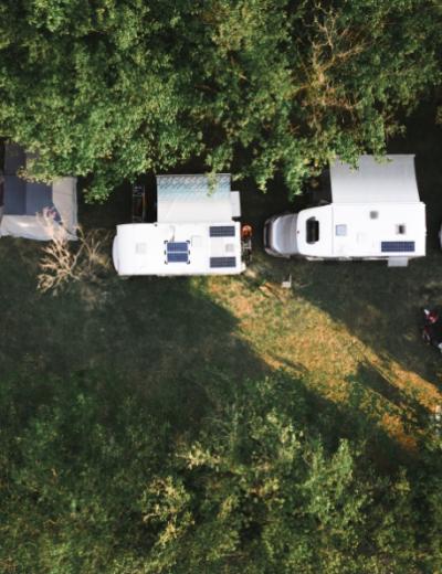 Vista aerea di camper parcheggiati in un'area verde, circondati da alberi.