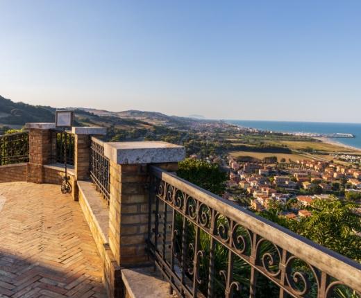 Vista panoramica sulla costa e sulla città da un balcone con ringhiera in ferro.