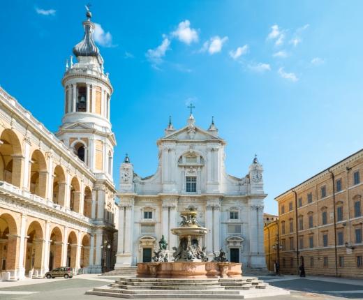 Piazza con basilica storica, fontana centrale e architettura rinascimentale.