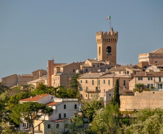 Vista panoramica di un borgo con una torre e bandiera italiana.