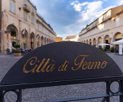 Piazza di un borgo italiano con edifici in mattoni e balconi in legno.