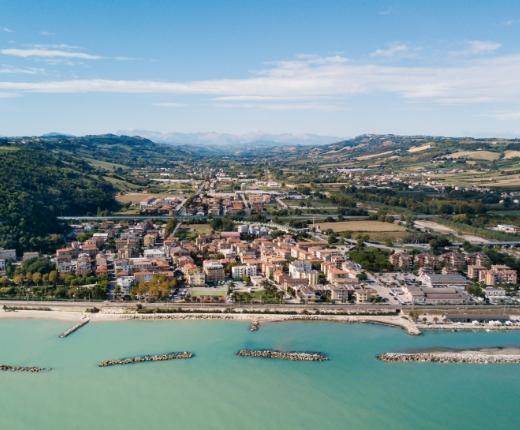 Vista aerea di una città costiera con colline e mare in primo piano.