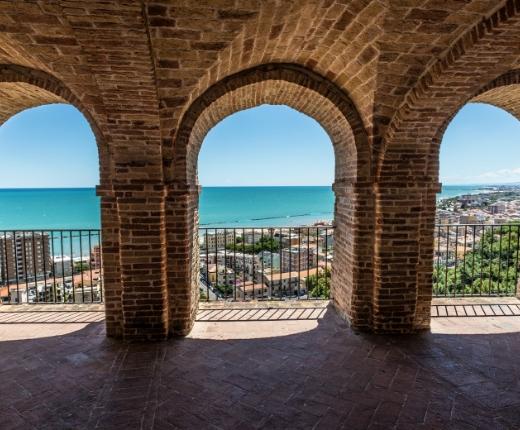 Vista sul mare attraverso archi di mattoni in una terrazza panoramica.